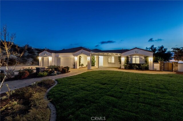 mediterranean / spanish home featuring an attached garage, a front yard, and stucco siding