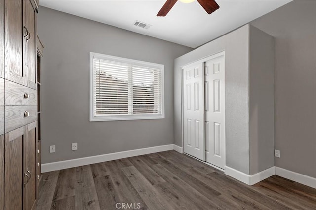 unfurnished bedroom featuring baseboards, visible vents, dark wood finished floors, and a closet