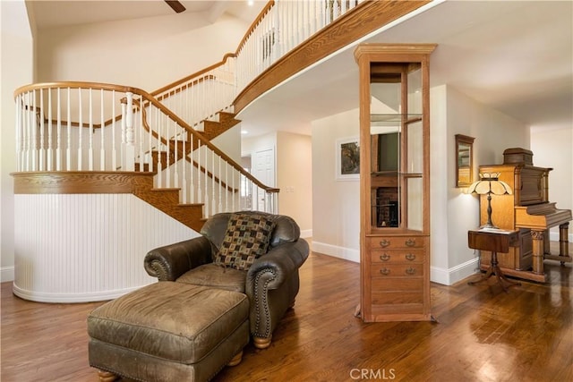 interior space featuring a towering ceiling, stairway, baseboards, and dark wood-type flooring