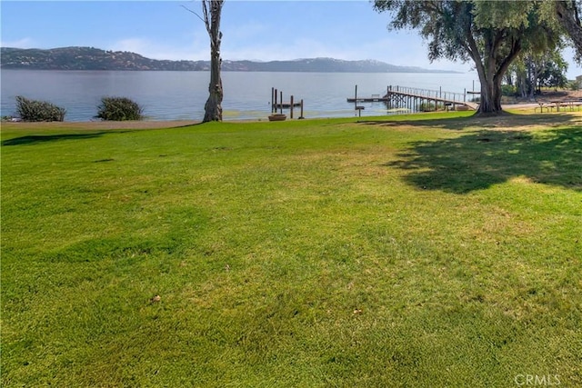 dock area featuring a lawn and a water and mountain view