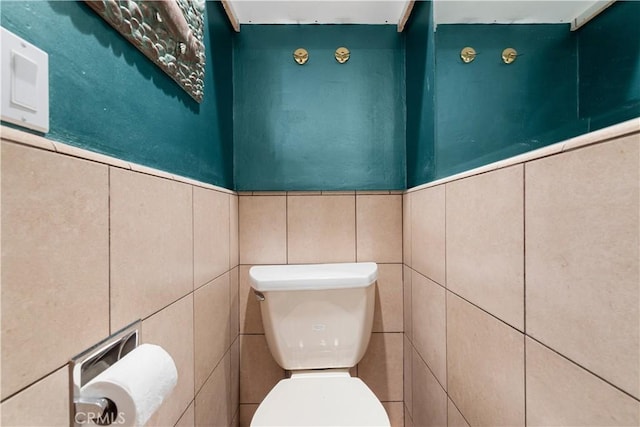 bathroom with toilet and tile walls