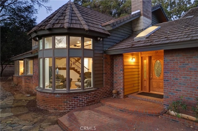 entrance to property featuring brick siding and a chimney