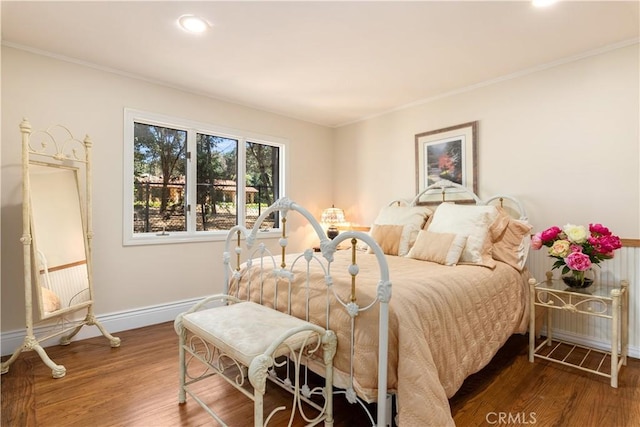 bedroom featuring dark wood-type flooring, radiator, crown molding, and baseboards