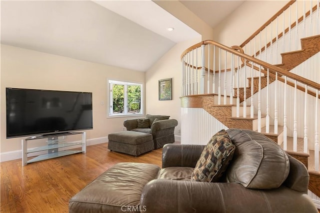 living room featuring lofted ceiling, stairway, baseboards, and wood finished floors