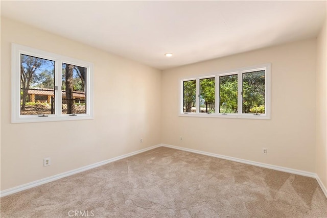 empty room featuring light colored carpet and baseboards