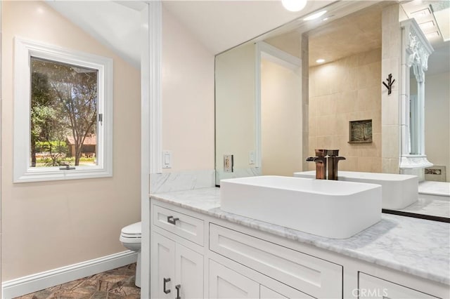 bathroom with toilet, a fireplace, baseboards, and vanity