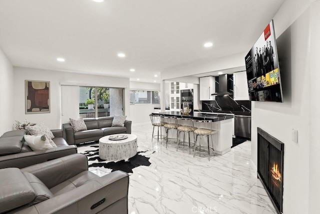 living room featuring recessed lighting, a lit fireplace, and marble finish floor