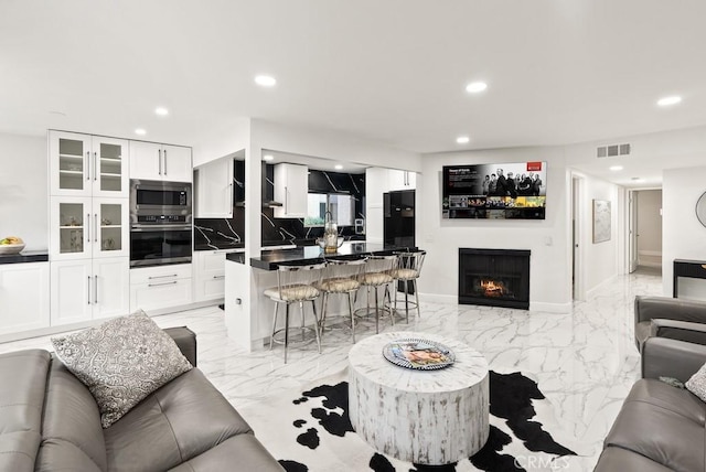 living room with recessed lighting, a lit fireplace, and marble finish floor