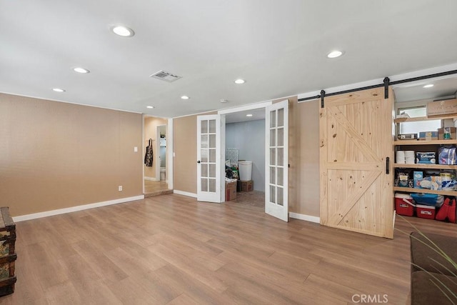 interior space with french doors, a barn door, and light hardwood / wood-style floors