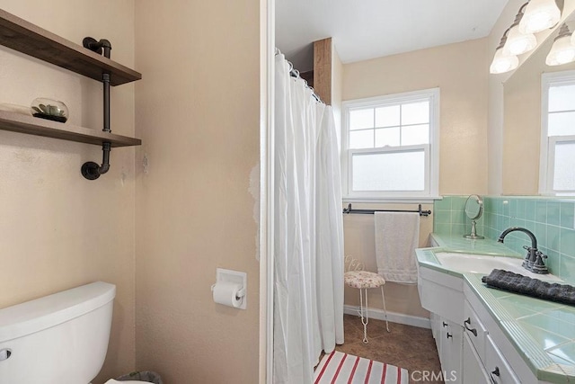 bathroom featuring vanity, decorative backsplash, toilet, and a healthy amount of sunlight