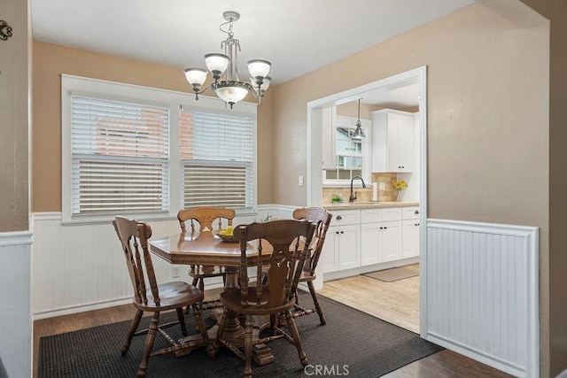 dining area featuring a notable chandelier, sink, and dark hardwood / wood-style floors