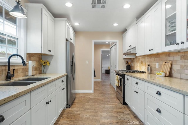 kitchen featuring white cabinetry, appliances with stainless steel finishes, sink, and decorative light fixtures