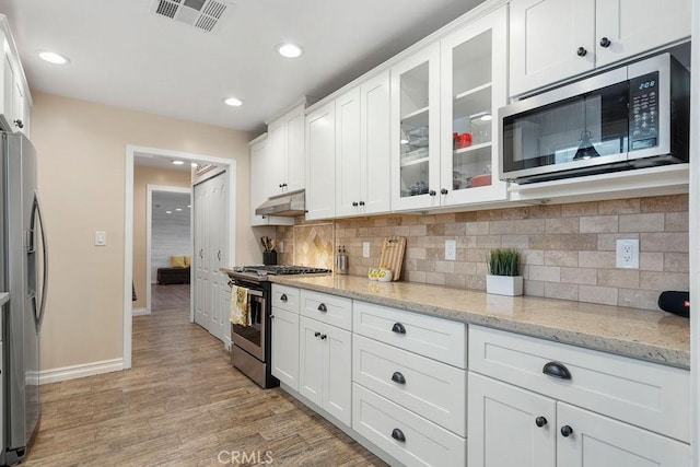 kitchen featuring appliances with stainless steel finishes, light stone countertops, light hardwood / wood-style floors, and white cabinets