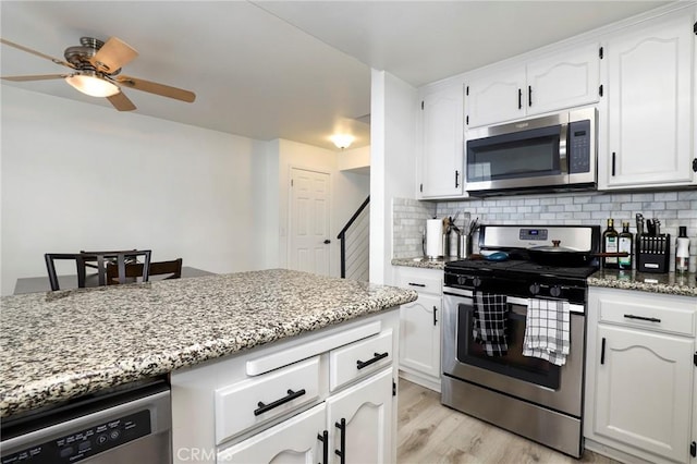 kitchen with white cabinetry, tasteful backsplash, stainless steel appliances, and light stone counters