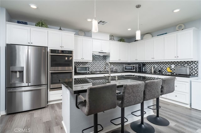 kitchen featuring hanging light fixtures, an island with sink, appliances with stainless steel finishes, and white cabinetry