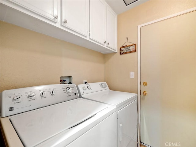 clothes washing area with cabinets and washer and clothes dryer