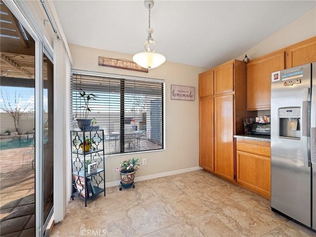 kitchen featuring lofted ceiling, stainless steel fridge, and hanging light fixtures