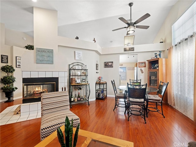 dining area featuring a tiled fireplace, hardwood / wood-style flooring, plenty of natural light, and vaulted ceiling