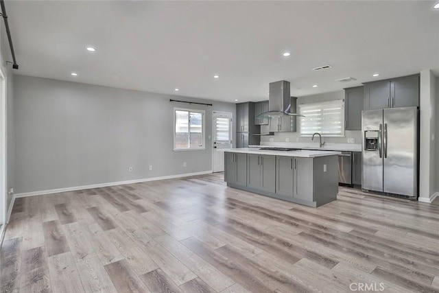 kitchen featuring gray cabinets, stainless steel appliances, a center island, island range hood, and light wood-type flooring