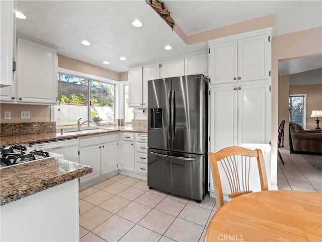 kitchen with sink, dark stone countertops, white cabinets, and stainless steel fridge with ice dispenser