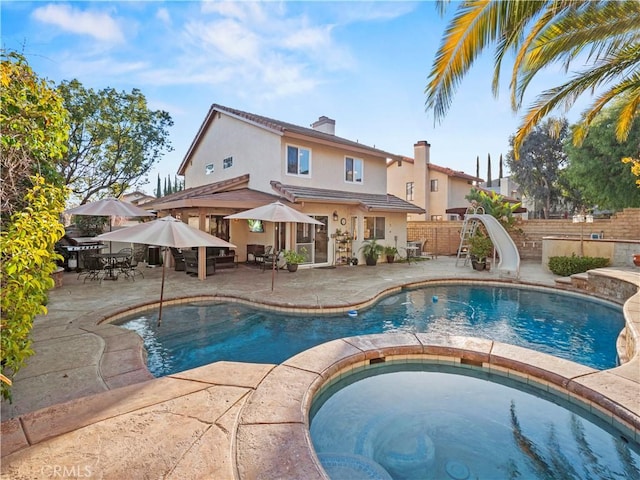 view of pool with an in ground hot tub, a water slide, and a patio