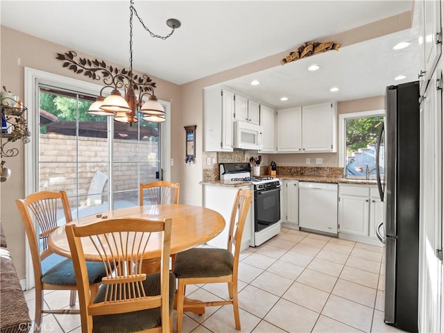 kitchen with pendant lighting, light tile patterned floors, white appliances, light stone counters, and white cabinets