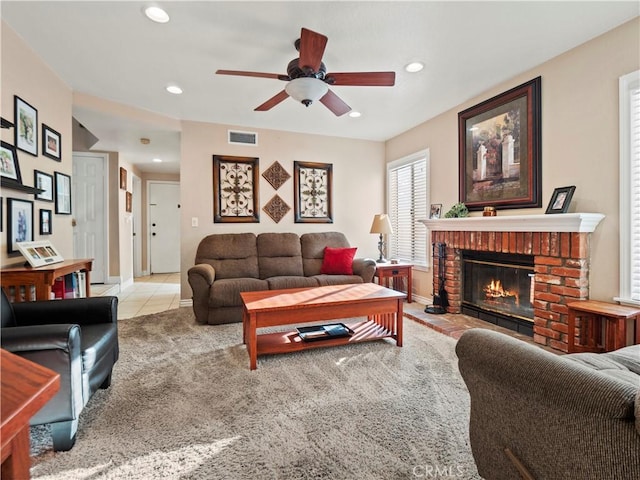 living room with ceiling fan, a fireplace, and light carpet