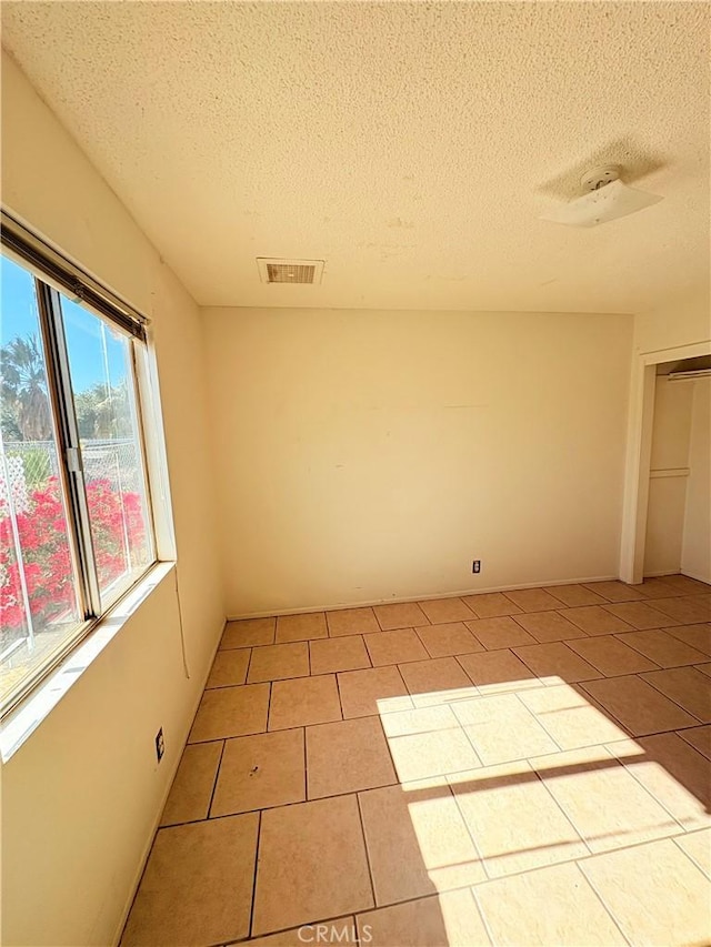 spare room featuring a textured ceiling and light tile patterned flooring