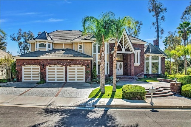 view of front of property with driveway, a garage, a chimney, and a tiled roof