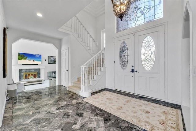 foyer with recessed lighting, a high end fireplace, stairs, marble finish floor, and an inviting chandelier