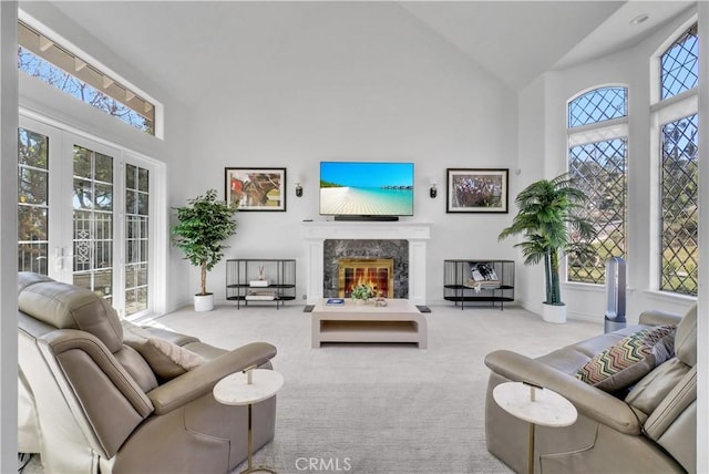 living room with high vaulted ceiling, a premium fireplace, and light colored carpet