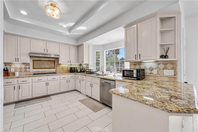 kitchen featuring stainless steel appliances, white cabinets, a peninsula, light stone countertops, and under cabinet range hood