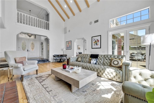 living room with arched walkways, french doors, visible vents, and wood finished floors