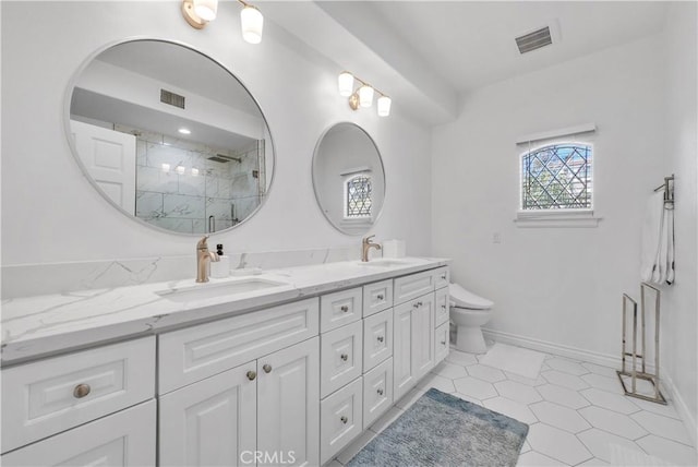 full bath featuring a sink, double vanity, a marble finish shower, and visible vents