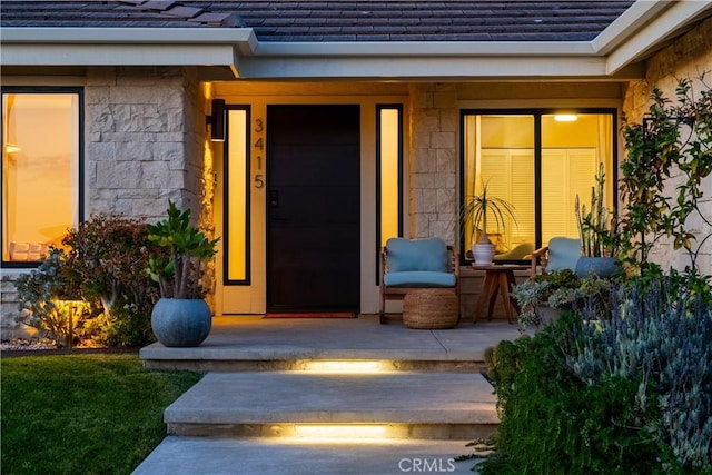 property entrance with stone siding and roof with shingles