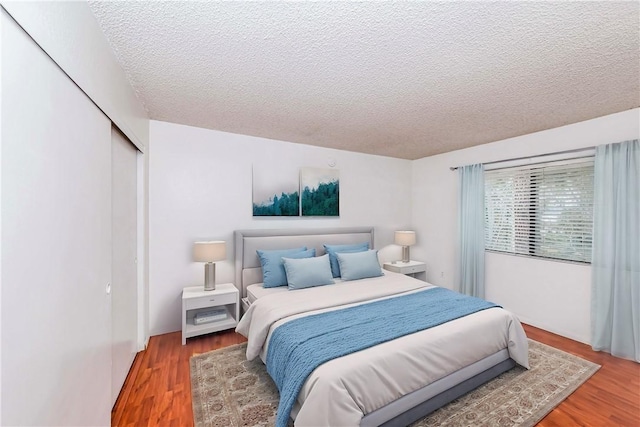 bedroom featuring hardwood / wood-style flooring, a textured ceiling, and a closet