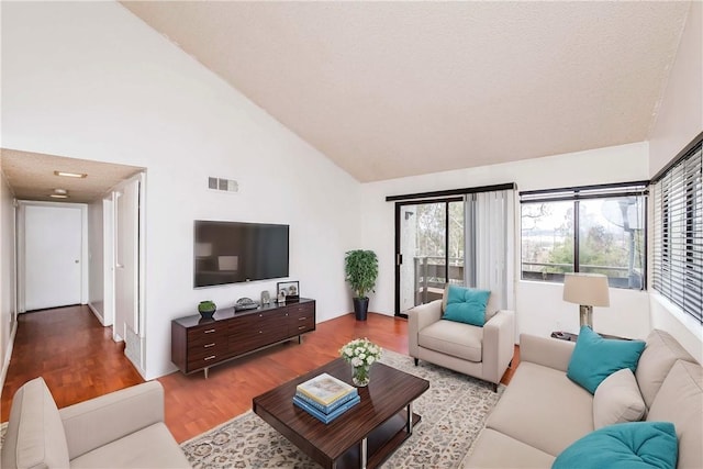 living room with high vaulted ceiling and light wood-type flooring