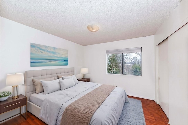 bedroom with dark hardwood / wood-style flooring, a textured ceiling, and a closet