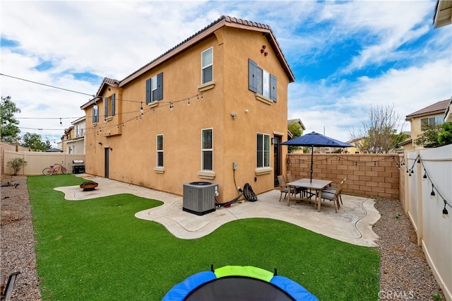 rear view of house featuring a fire pit, a lawn, a patio, and central air condition unit