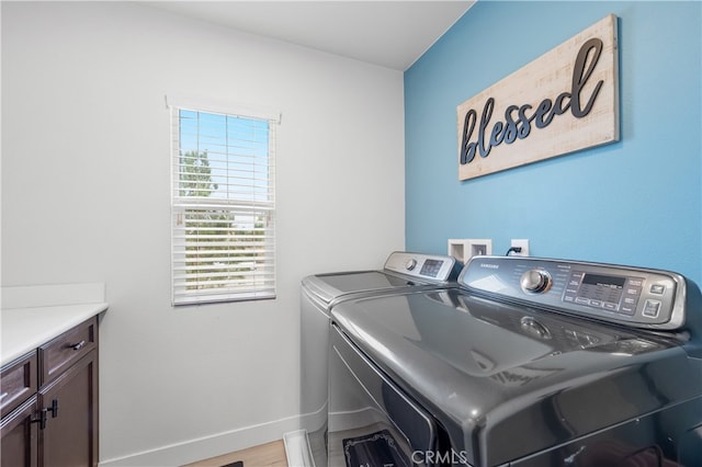 laundry room featuring washer and clothes dryer and cabinets