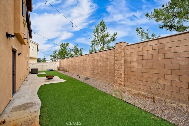 view of yard featuring a fire pit, a patio area, and central AC