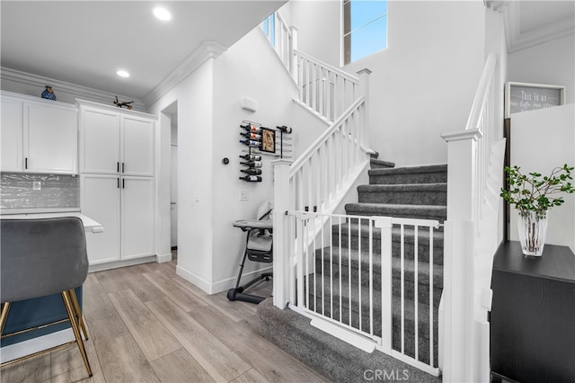 stairway with crown molding and hardwood / wood-style flooring