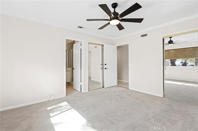 unfurnished bedroom featuring two closets, ornamental molding, light colored carpet, and ceiling fan