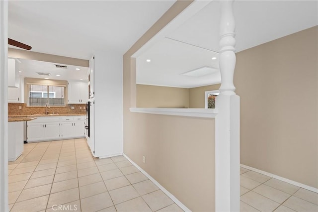 interior space with light stone countertops, sink, light tile patterned floors, and white cabinets