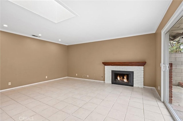 unfurnished living room with ornamental molding, a fireplace, a skylight, and light tile patterned floors