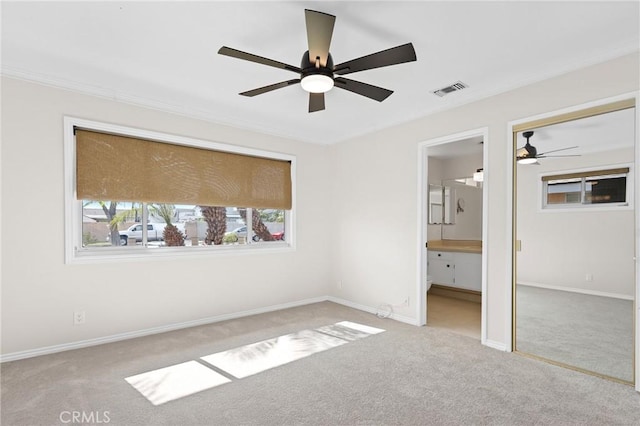 unfurnished bedroom with crown molding, light colored carpet, ceiling fan, and ensuite bathroom