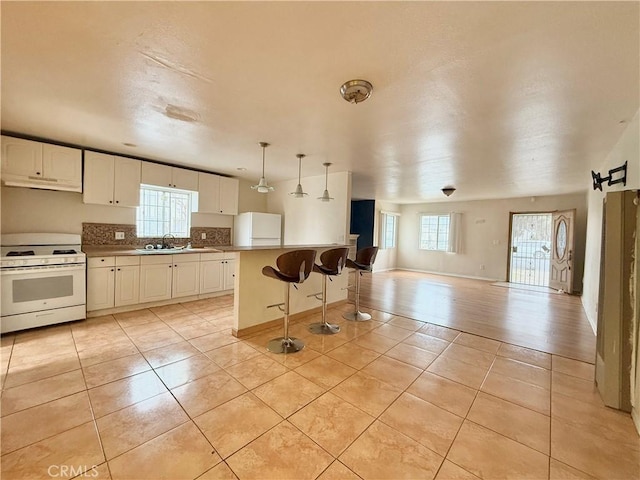 kitchen featuring white cabinetry, hanging light fixtures, white appliances, and a center island