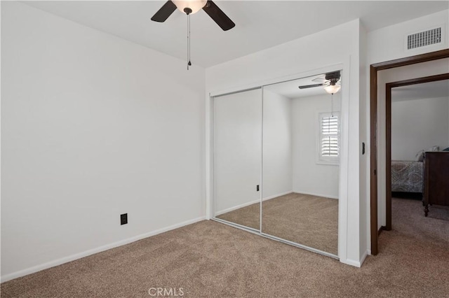 unfurnished bedroom featuring light colored carpet, ceiling fan, and a closet