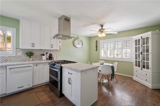 kitchen featuring white cabinetry, backsplash, white dishwasher, island range hood, and range with two ovens