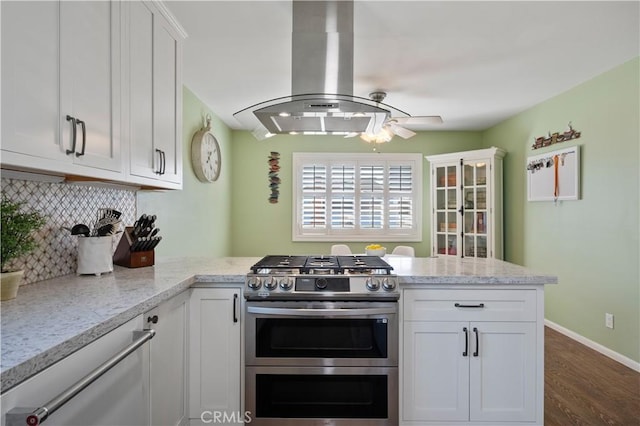 kitchen with white cabinetry, light stone counters, island range hood, double oven range, and decorative backsplash